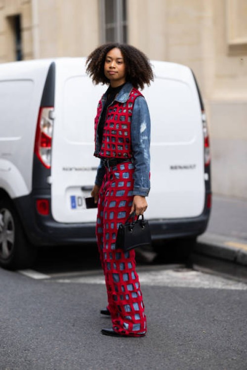 Guest is seen wearing black leather shoes, a black leather bag, a black belt, a black top and a red fishnet and blue jeans coord-set made of a...