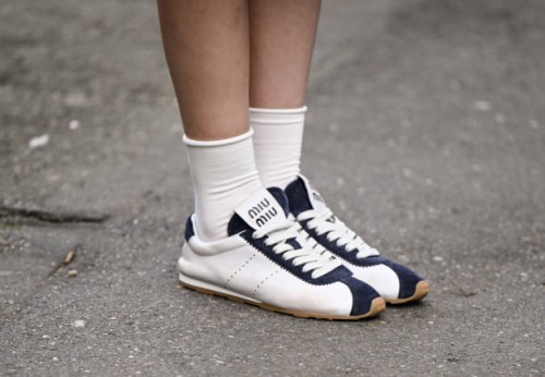 Guest is seen wearing white and blue Miu Miu sneakers with white socks outside the Miu Miu show during the Womenswear Fall/Winter 2025/2026 as part...
