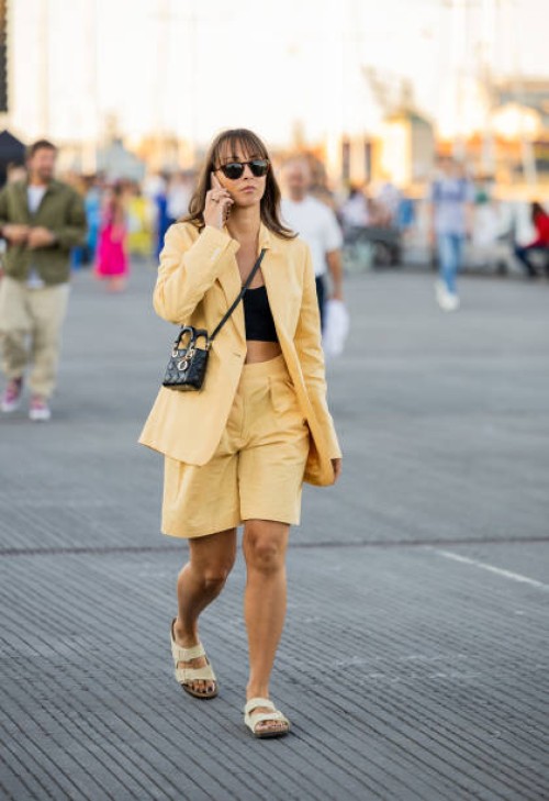 Guest is seen wearing yellow blazer, shorts, black Dior bag outside Ganni during Copenhagen Fashion Week Spring/Summer 2023 on August 11, 2022 in...