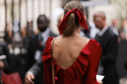 Guest seen outside Zuhair Murad show wearing red hair bow, red open back dress and Hermes Kelly bag in brown with gold hardware during the Haute...