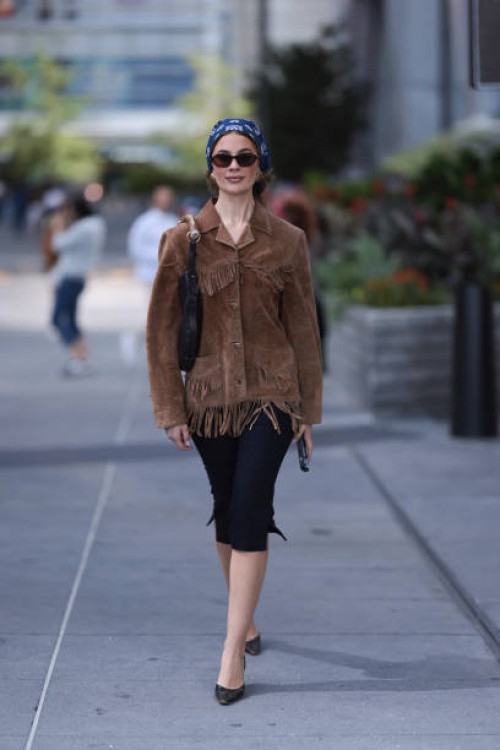 Guest seen wearing a blue pattern bandana headband, gold round earrings, DMY Studios black oval sunglasses, vintage brown suede leather jacket with...
