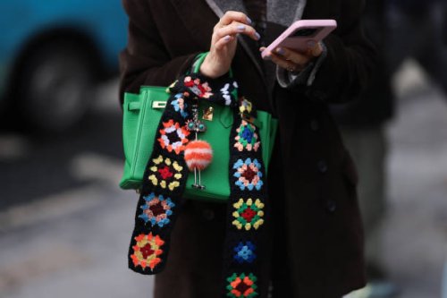 Guest seen wearing a brown wool coat, black and denim jeans pants, green Hermes Birkin bag with color printed statements, brown sunglasses and an...