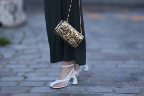 Guest seen wearing a grey long skirt, brown fur jacket, white heels, golden leo printed Celine handbag outside Stella McCartney show, during the...