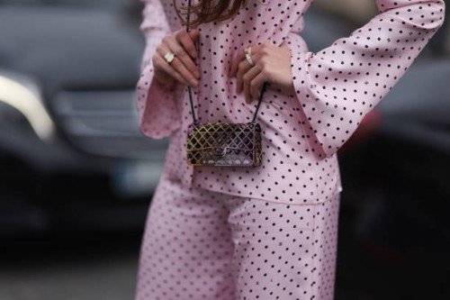 Guest seen wearing black sunglasses, a pink Chanel pyjama with flared pants and printed polka dots, a Chanel mini bag, platform black shoes, outside...