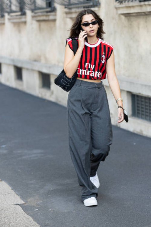 Guest, wearing an AC Milan shirt and grey pants, poses ahead of the Prada fashion show during the Milan Fashion Week - Spring / Summer 2022 on...