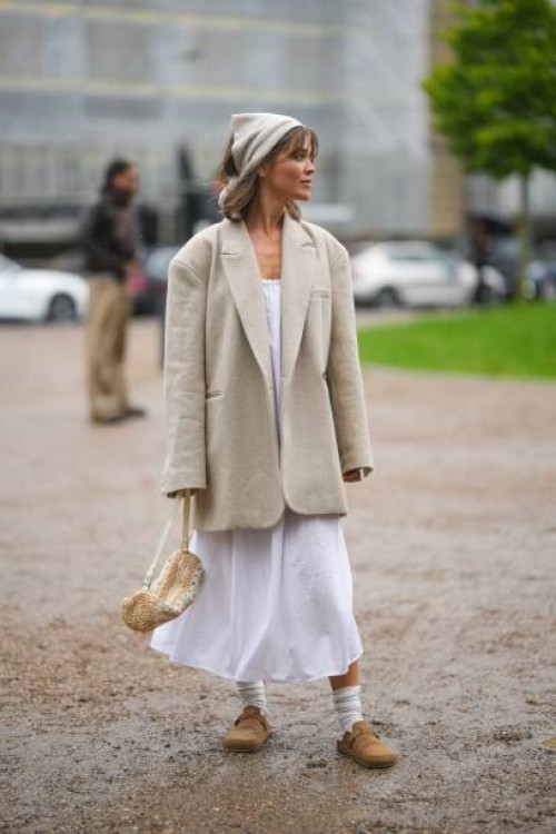 Guest wears a beige silk scarf as a headband, a white long dress, a beige oversized blazer jacket, a beige and white latte striped print pattern...