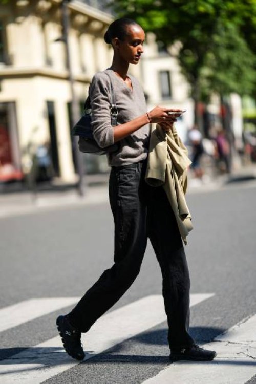 Guest wears a beige wool pullover, a black shiny leather shoulder bag, a beige blazer jacket, black denim large pants, black suede and fabric...