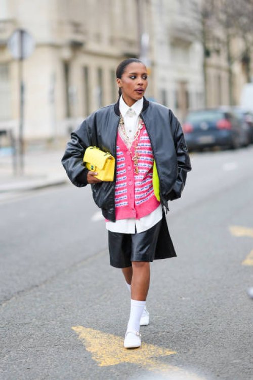 Guest wears a black bomber jacket , a white shirt, a yellow quilted leather Chanel bag, a pink tweed cardigan, a black leather skirt , white socks,...