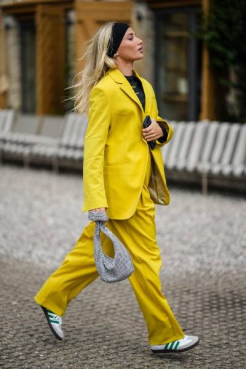Guest wears a black large headband, a black t-shirt, a yellow oversized blazer jacket, yellow large suit pants, a gray satin with rhinestones mesh /...
