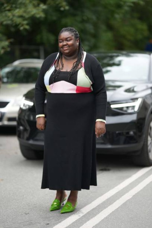 Guest wears a black ribbed long sleeves long dress with pale pink / red / blue print pattern tank-top, green shiny leather pointed heels shoes mules...