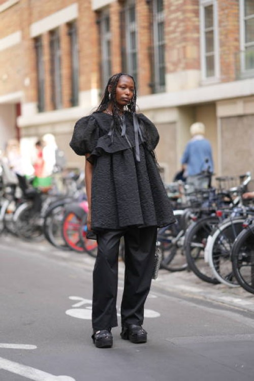 Guest wears a black textured ruffled dress, black pants, outside Cecilie Bahnsen, during the Womenswear Spring/Summer 2024 as part of Paris Fashion...