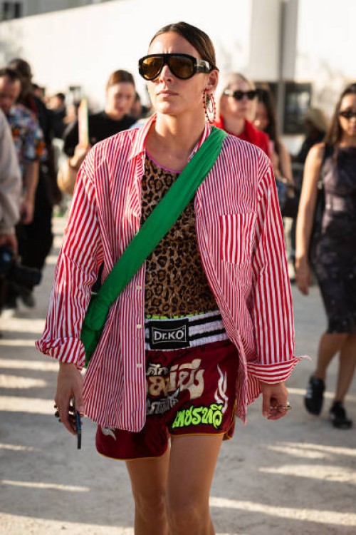 Guest wears a leopard print top, red striped shirt, sporty shorts and green bag, outside Casablanca, during the Womenswear Spring/Summer 2024 as part...