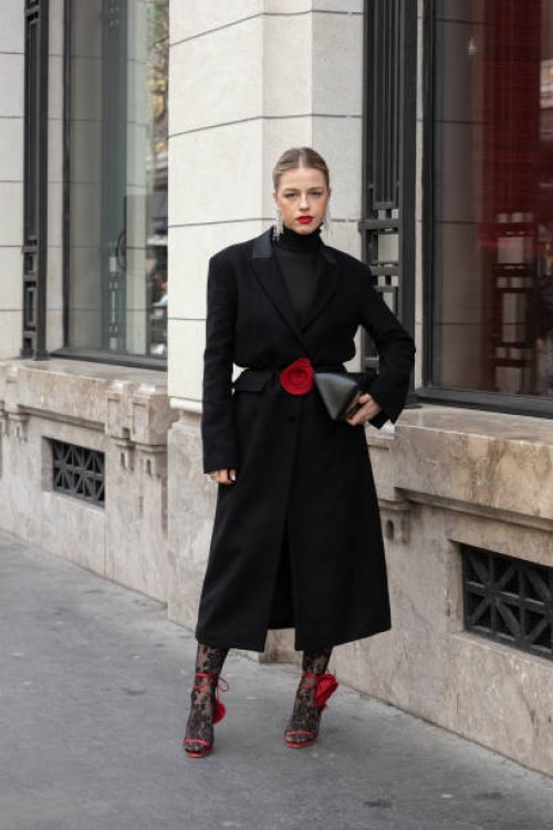 Guest wears a long black coat, black turtleneck top, red shoes, leggings and black bag outside Magda Butrym during the Womenswear Fall/Winter...