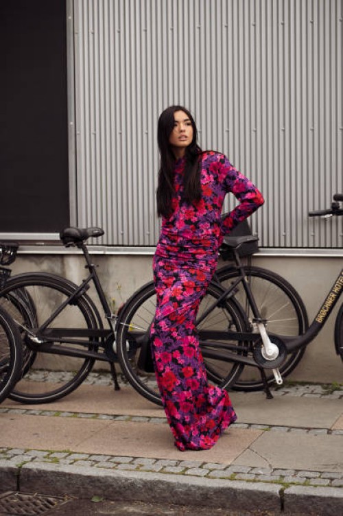 Guest wears a long maxi dress in purple, red, and pink color combination outside Gestuz during the Copenhagen Fashion Week Spring/Summer 2024 on...