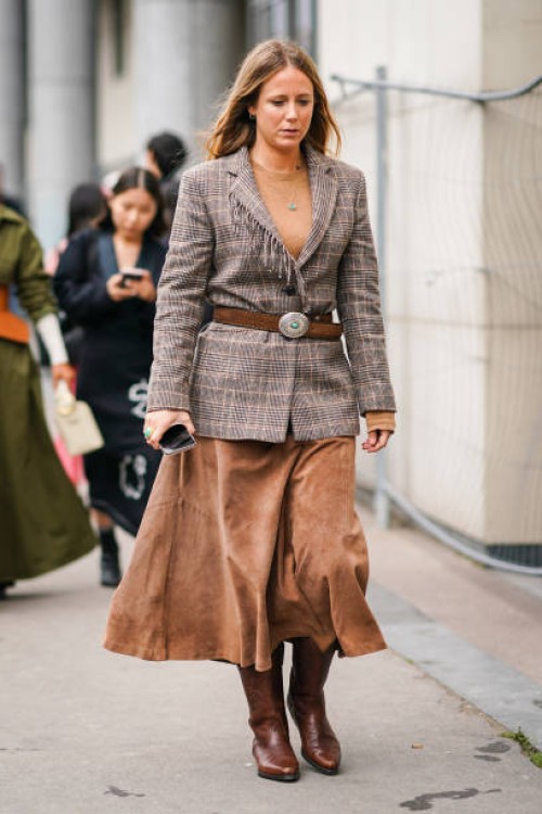 Guest wears a necklace, a camel top, a grey and brown Prince of Wales check fringed jacket, a brown cowboy belt, a light brown leather skirt, brown...