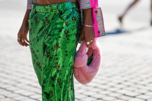 Guest wears a neon pink and green striped print pattern jacket, a silver chain bracelet, silver rings, green sequined with black and gold small...