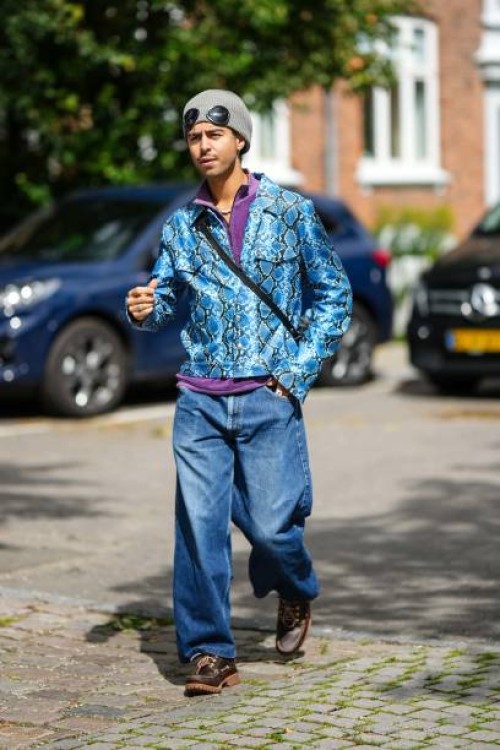 Guest wears a pale gray felt wool beret, black sunglasses, a purple zipper high neck polo shirt, a blue and black shiny leather snake print pattern...