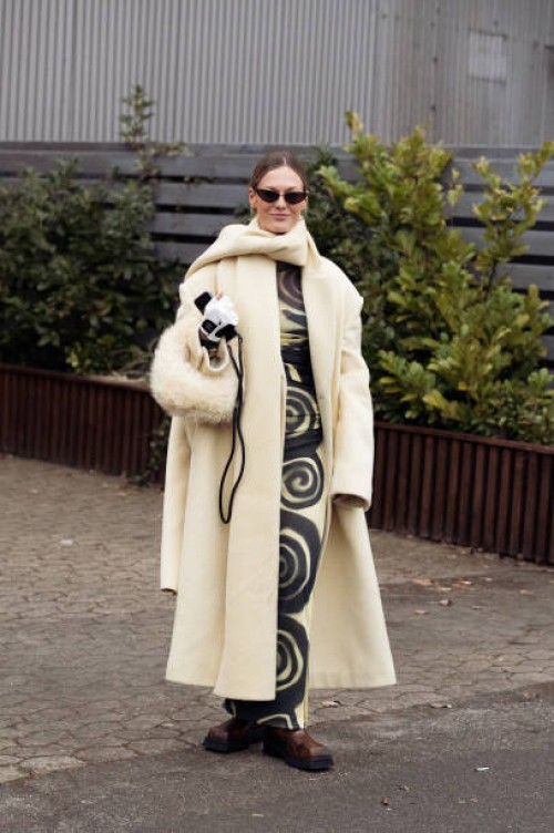 Guest wears a pale yellow and black long dress, pale yellow coat, matching fur bag, white and black Chanel gloves, and matching long scarf outside...