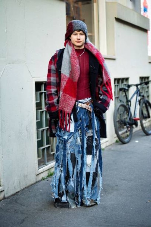 Guest wears a red and grey checked knitted maxi scarf, a red sweater, a red, black and grey checked coat, a white belt and denim ripped wide leg...