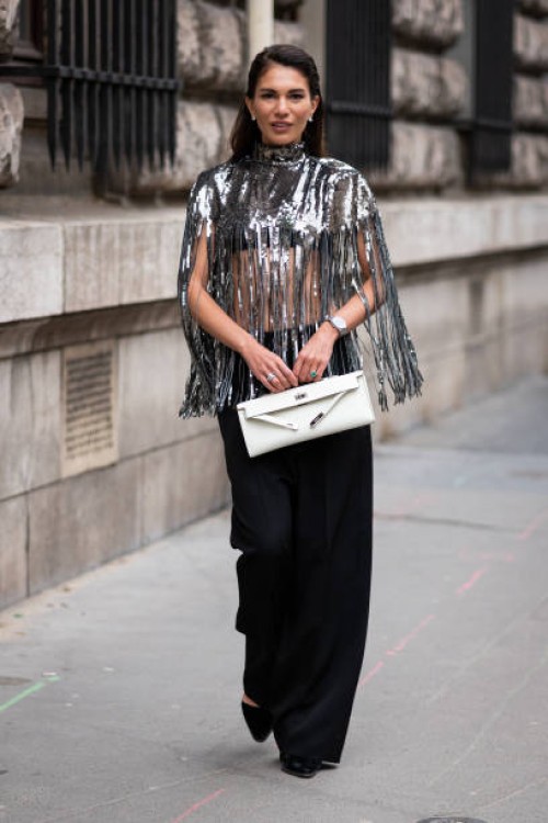 Guest wears a silver fringed sequins top, black pants, white bag, outside Hermes, during Paris Fashion Week - Womenswear Fall Winter 2023 2024, on...