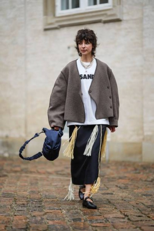 Guest wears a silver large chain necklace, a white pearls necklace, a white with black logo print pattern t-shirt from Jil Sander, a dark gray...