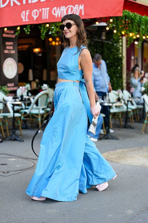 Guest wears a sleeveless, light blue crop top paired with matching high-waisted, wide-leg trousers. The ensemble appears to be made of a lightweight...