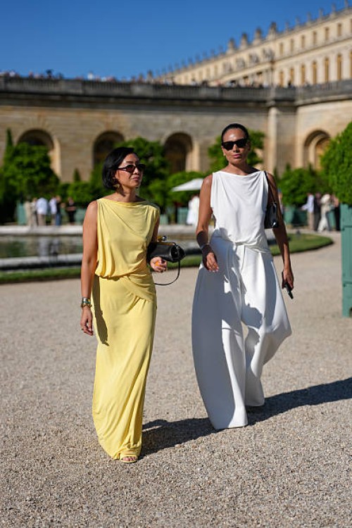 Guest wears a sleeveless yellow dress with a draped neckline and gathered waist detail. The fabric appears lightweight and flowing. Accessories...