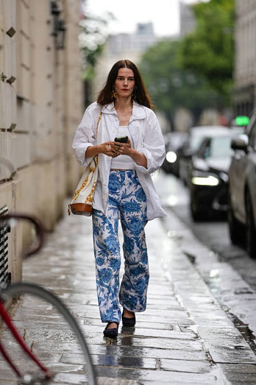 Guest wears a white oversized button-up shirt with long sleeves, layered over a white ribbed tank top. The pants feature a blue and white floral...