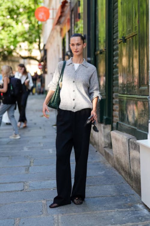 Guest wears a white shirt, light gray button up cardigan sweater, dark green Bottega Veneta leather bag, black loose pants, black sheer mesh flat...