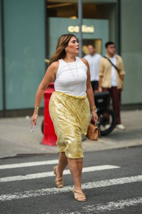 Guest wears a white tank top, a yellow shiny sequined on-knee skirt, beige sandals, outside Proenza Schouler, during New York Fashion Week, on...