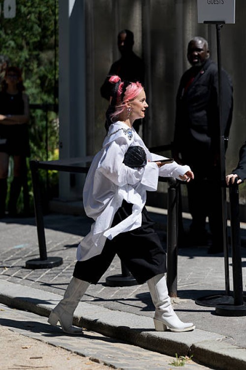 Guest wears an oversized white button-up shirt adorned with jeweled brooches and a silver chain detail, black wide-leg cropped trousers, white...