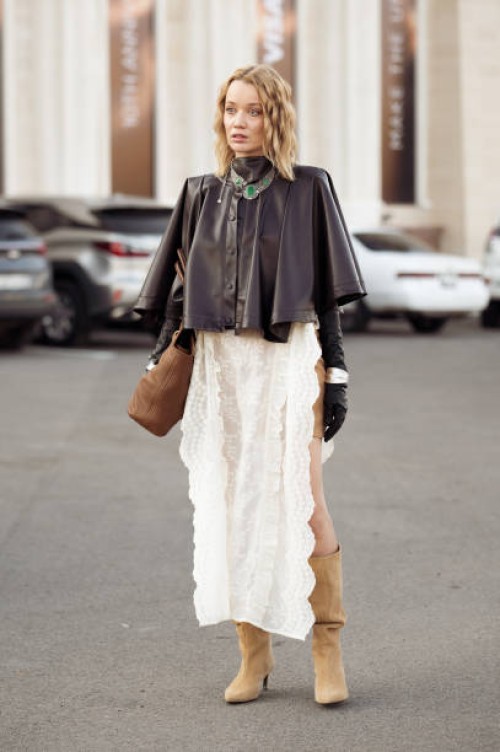 Guest wears beige mini skirt, long beige boots, white long lace skirt, dark brown leather jacket, black leather gloves and brown bag during the 10th...