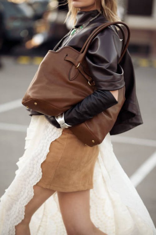 Guest wears beige mini skirt, white long lace skirt, dark brown leather jacket, black leather gloves and brown bag during the 10th season of the Visa...