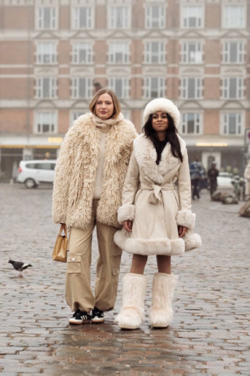 Guest wears beige pants, and a beige fur coat, and a guest wears a light beige coat with fur, fur hat, and fur boots outside Rolf Ekroth during the...