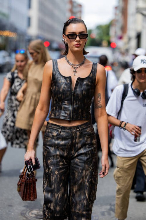 Guest wears black brown leather pants, zipper top outside Gestuz during day four of the Copenhagen Fashion Week SS25 on August 08, 2024 in...