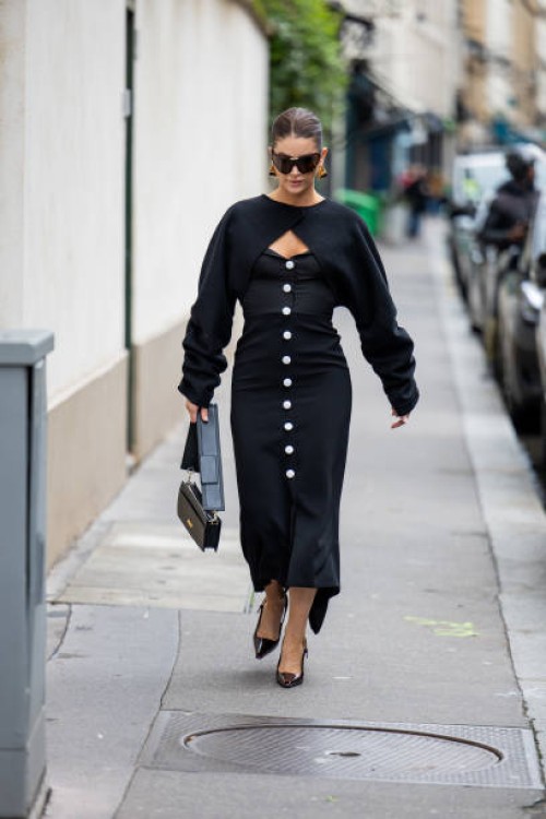 Guest wears black button up dress, cut out jumper, bag outside Valentino during the Womenswear Fall/Winter 2024/2025 as part of Paris Fashion Week on...