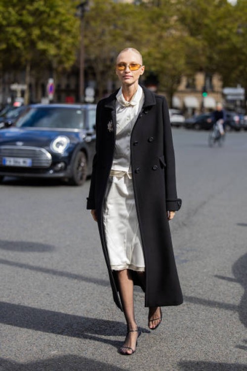 Guest wears black coat, white skirt, blouse outside Miu Miu during Womenswear Spring/Summer 2025 as part of Paris Fashion Week on October 01, 2024 in...