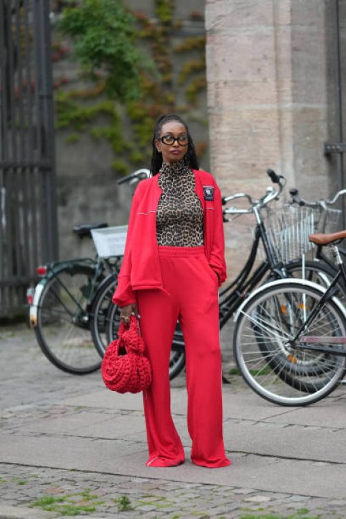 Guest wears black glasses, a brown / beige and black leopard print pattern turtleneck t-shirt, a neon red zipper sport sweater, matching neon red...