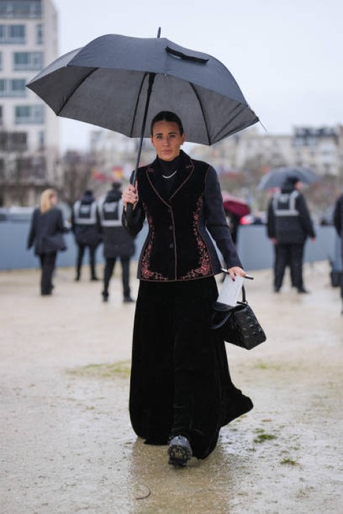 Guest wears black high neck long sleeve shirt, silver necklace, burgundy black tailored velvet butterfly embroidered Dior blazer jacket, black maxi...