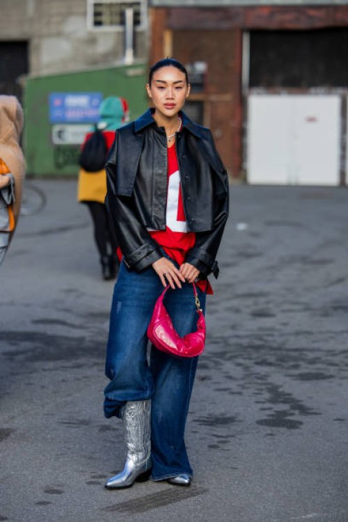Guest wears black leather jacket, denim jeans, silver cowboy boots, red bag outside Gestuz during the Copenhagen Fashion Week AW24 on February 01,...