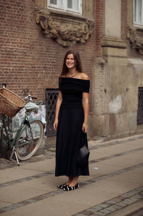 Guest wears black long dress and cow print ballerina shoes outside the Gestuz show during day four of the Copenhagen Fashion Week SS25 on August 08,...
