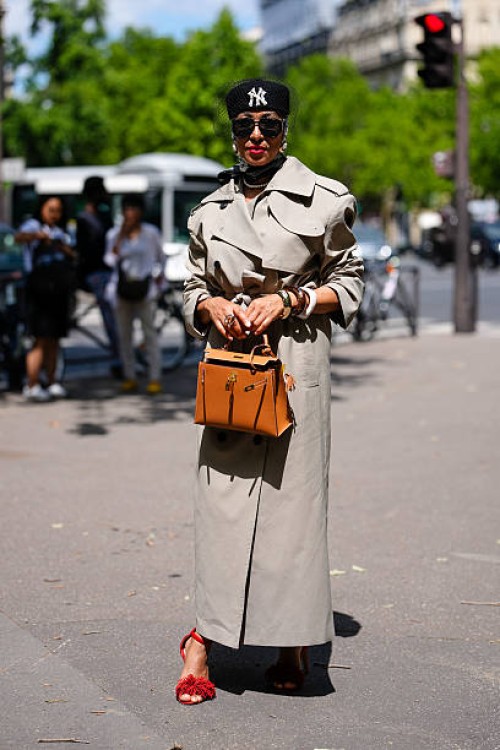 Guest wears black New York Yankee pillbox hat with sheer mesh covering, black sunglasses, white black pattern silk head scarf, pearl necklace, light...