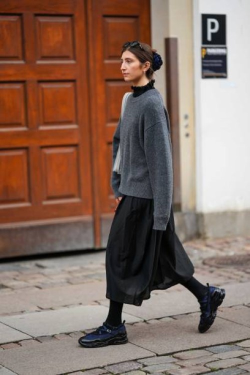 Guest wears black sunglasses, a black turtleneck top, a dark gray wool pullover, a pale gray leather shoulder bag, a black midi skirt, black tights,...