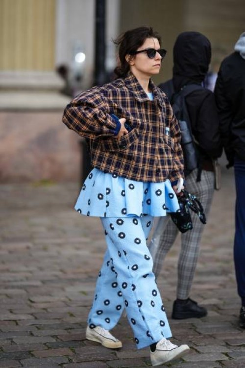 Guest wears black sunglasses, a dark brown and black checkered print pattern jacket, a pale blue with black and white circle print pattern ruffled...
