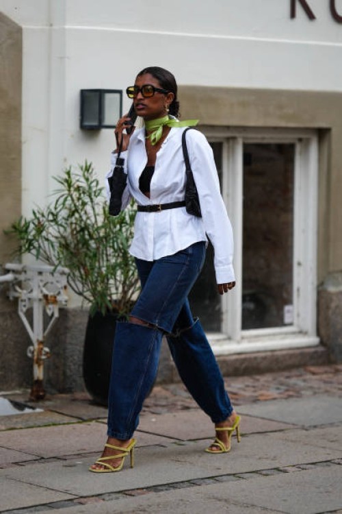 Guest wears black sunglasses, a green silk scarf, a white shirt, a black shoulder-off top, a black shiny leather shoulder bag, a black shiny leather...