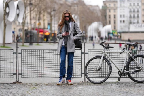 Guest wears black sunglasses, a grey scarf, a grey blazer jacket, dark blue pants, white and grey Nike sneakers shoes, outside Hed Mayner, during the...