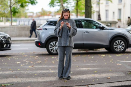 Guest wears black sunglasses, a grey wool turtleneck pullover, matchings pants, dark green sneakers shoes, during Womenswear Spring/Summer 2025 as...