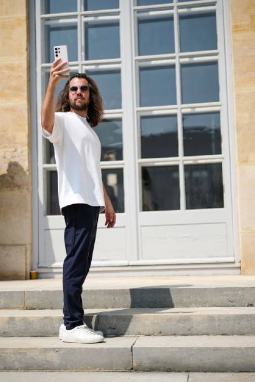 Guest wears black sunglasses, a white t-shirt, navy blue suit pants, white leather laces sneakers , outside Dior , during the Haute Couture...
