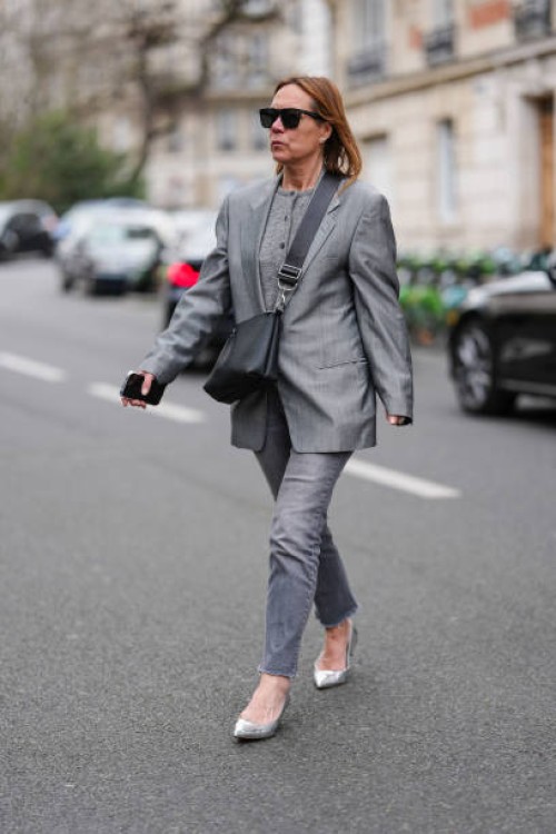 Guest wears black sunglasses, dark gray buttoned cardigan sweater, dark gray oversized blazer jacket, shiny black leather bag, dark gray denim jean...