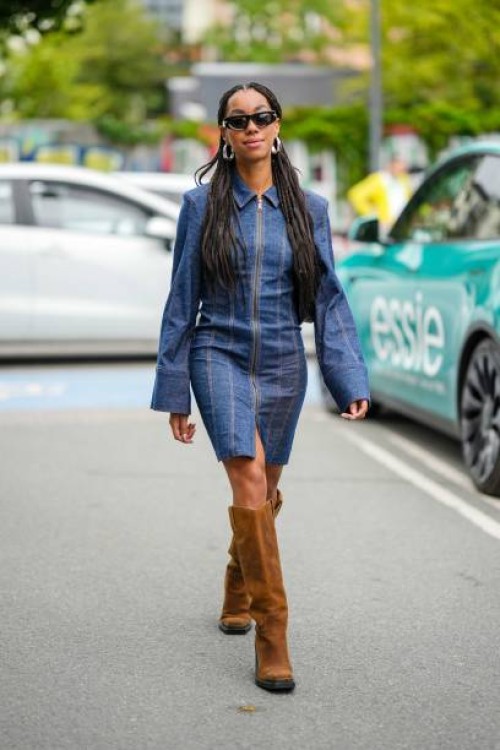 Guest wears black sunglasses, silver large earrings, a navy blue denim shirt neck / long flared sleeves / zipper short dress, dark brown suede knees...